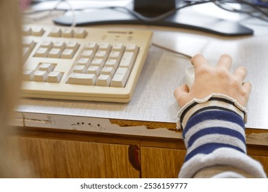 a child's hand controls an old ball mouse with cable on a very old computer to explore the past of the computer industry - Powered by Shutterstock