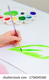 Child's Hand Drawing Green Leaf By Watercolors On White Sheet Of Paper. Earth Day Concept.