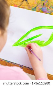 Child's Hand Drawing Green Leaf By Watercolors On White Sheet Of Paper On An Easel. Earth Day Concept.