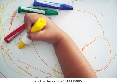 A child's hand is drawing using crayons. DIY, kids and art, creativity and creation, art class, circle activity, abstract concept. 