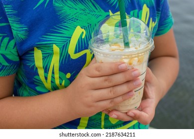 Child's Hand Drinking Cold Coffee With Iced Caramel.