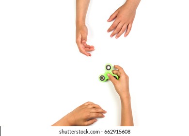 Child's Hand Giving Fidget Spinner To Another Child Hands On White Background. Top View