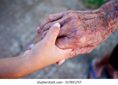 A Child's Hand Holding The Hand Of An Old Man.