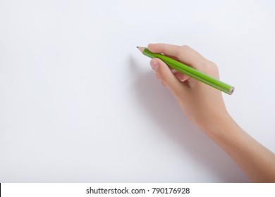 The Child's Hand Holding A Pencil Against A White Sheet Of Paper