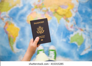 Child's Hand Holding US Passport. Map Background. Ready For Traveling. Open World.