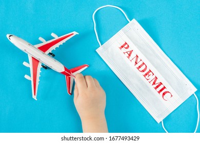 A Child's Hand Holds A Toy Airplane, Next To A Medical Mask With The Inscription Pandemic. Evacuation Of People From Areas Infected With Coronavirus.