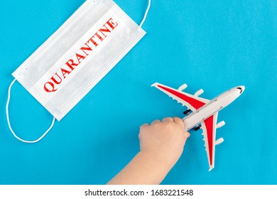 A Child's Hand Holds A Toy Airplane, Next To A Medical Mask With The Inscription Quarantine. Evacuation Of People From Areas Infected With Coronavirus.