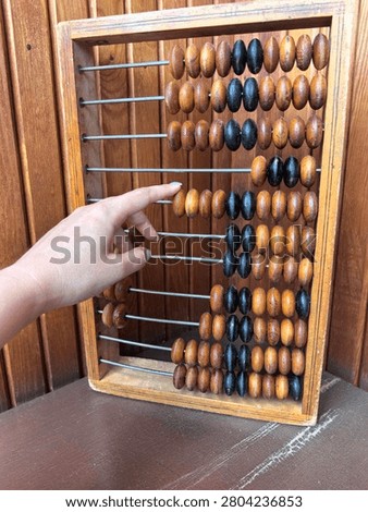 Child's hand learning to count using traditional wooden abacus, early math education and numeracy skills concept