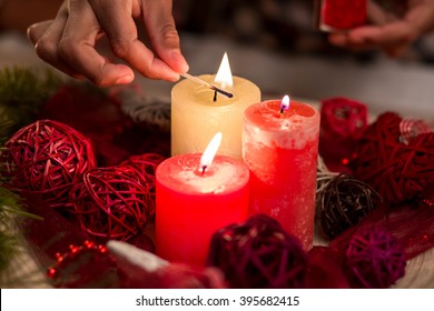 Child's hand lighting Christmas candles. Close-up of candles being lit. Candles and red wire balls. Symbolic Christmas decorations. - Powered by Shutterstock