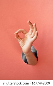 A Child's Hand Makes A Sign, Everything Will Be Fine, OK.Trend Hand In A Hole Made Of Pink Paper.