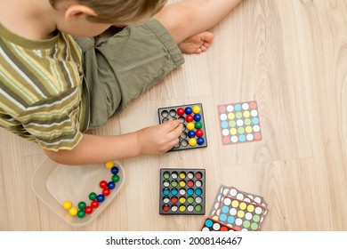 Childs hand on colorful wooden marbles. Color sequence logic game. A tool for pre-school and primary education. Montessori, brain exercise. Focus, patience and attention practice. 