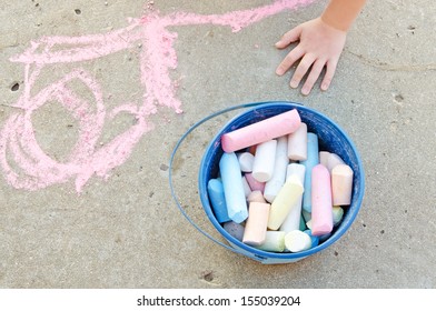 Child's Hand And Pail Of  Chalk On Sidewalk