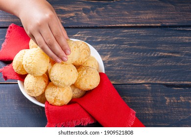 A child's hand picking up a Brazilian cheese bread. Also known in Latin America as Chipa, Pan de Bono and Pan de Yuca.