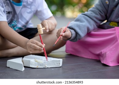 Child's Hand Is Playing With The Archaeological Set. Child Digging A Dinosaur. Two Child Have Fun With Archaeology Excavation Kit.