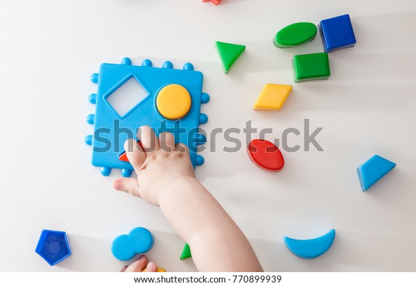 Child's hand, playing with toys.,
educational toys, arranging and sorting colors and
sizes.