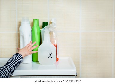 Child`s Hand Reaches Out To Household Chemicals. Keep Away From Children. Safety Hazard For Kids At Home.