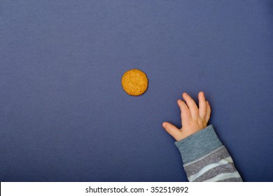 Child's Hand Reaching For Cookie On The Table. Baby Taking A Food.