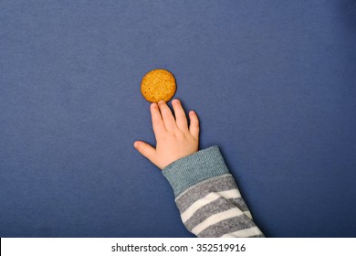 Child's Hand Reaching For Cookie On The Table. Baby Taking A Food.