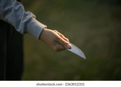 A child's hand with a sharp knife. Child crime at school. The knife is in the boy's hand.