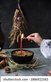a child's hand in traditional Ukrainian clothes lights a candle in a kutya. traditional orthodox Christmas food. christmas evening