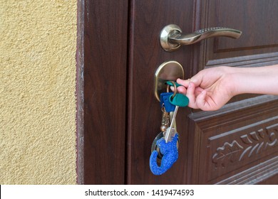 Child's Hand Unlocking Entrance Door With A Key. Person Using Keys And Locking Apartment Door.