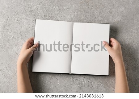 Child's hands with blank book on light background, closeup