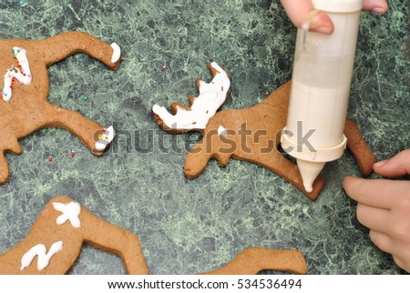 Child's hands decorating Christmas cookies in the shape of Christmas reindeer Santa Claus