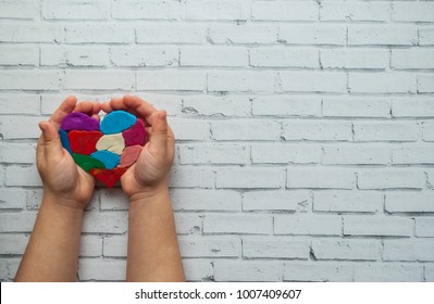 Child's hands holding a multicolored heart on white background with place for your text. World autism awareness day concept. - Shutterstock ID 1007409607