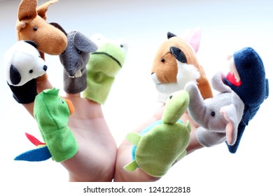 Child's hands with multi coloured toys of animals on each finger against a white background. Play with finger puppet in the nursery for children's activities concept. Happy teachers day. Close up - Powered by Shutterstock