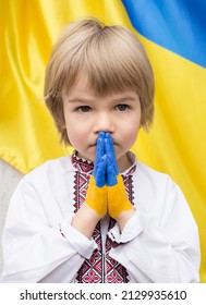 child's hands are painted in colors of Ukrainian flag. boy in national clothes asks for help. children's prayer to stop war in Ukraine. Prayer, Faith, Hope. asking for help from world community