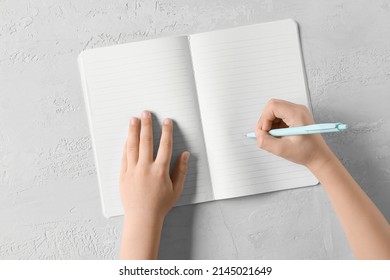 Child's hands with pen and notebook on light background - Powered by Shutterstock