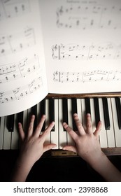 child's hands playing on a old piano