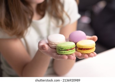 Child's hands taking French macarons of colorful macarons isolated on white table. Kid girl plays macarons cookie. Dessert person, sweet tooth, gourmet