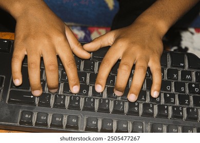 A child's hands typing on a computer keyboard, with the focus on the hands and keyboard, and the background is blurred.