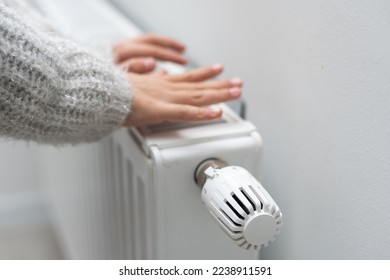 The child's hands warm their hands near the heating radiator. Saving gas in the heating season.