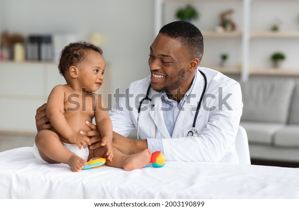 Child\'s\
Healthcare Concept. Portrait Of Smiling Black Doctor Making Check\
Up For Little Infant Baby Boy, Cute Toddler Child In Diaper Having\
Appointment At Pediatrician\'s Office, Free\
Space