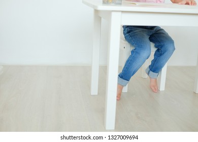 Child's Legs Of Child Girl View Under The Table