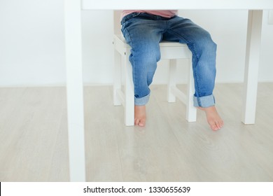 Child's Legs Of Child Girl View Under The Table