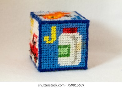 Child's Needlepoint Alphabet Block With Letter J And Image Of A Jar. White Background.