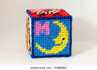 Child's Needlepoint Alphabet Block With Letter M And Image Of A Moon. White Background.