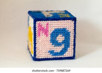 Child's Needlepoint Alphabet Block With Letter N And Image Of The Number Nine. White Background.