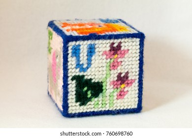 Child's Needlepoint Alphabet Block With Letter V And Image Of Violets. White Background.