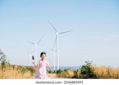 Child's playful exploration by windmills, little girl runs with pinwheels. Embracing wind energy education promoting clean electricity and sustainable industry in a beautiful setting. - Powered by Shutterstock