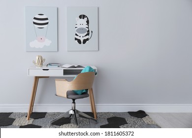 Child's Room Interior With Desk And Cute Posters On Light Wall. Space For Text