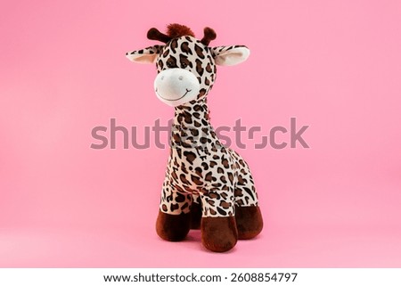 Child's stuffed giraffe toy on pink isolated background.