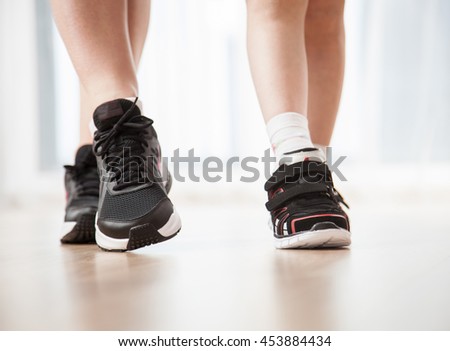 Child's and woman's legs in sports shoes, closeup shot