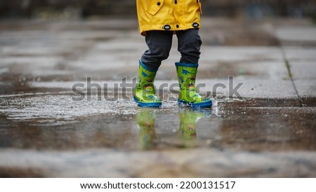 Similar – Image, Stock Photo Small infant boy wearing yellow rubber boots and yellow waterproof raincoat standing in puddle on a overcast rainy day. Child in the rain.