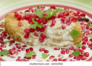 Chile en Nogada Mexican dish made from a poblano chile with a fried egg cover, walnut sauce and pomegranate seeds for flavor.