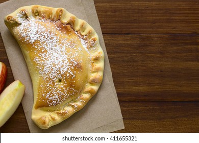 Chilean Apple Empanada With Icing Sugar, Photographed Overhead On Dark Wood With Natural Light