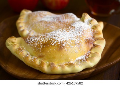 Chilean Apple Empanada With Icing Sugar, Photographed On Dark Wood With Natural Light (Selective Focus, Focus One Third Into The Image)